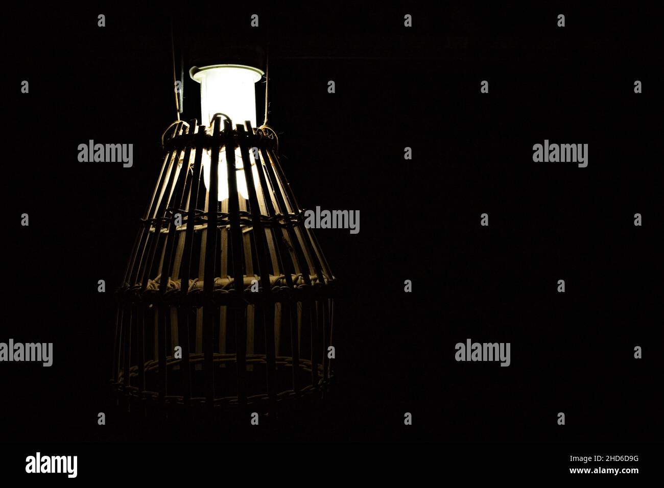 Una lampada con paralumi di una gabbia in bambù in luci basse. Punti di messa a fuoco selettivi Foto Stock