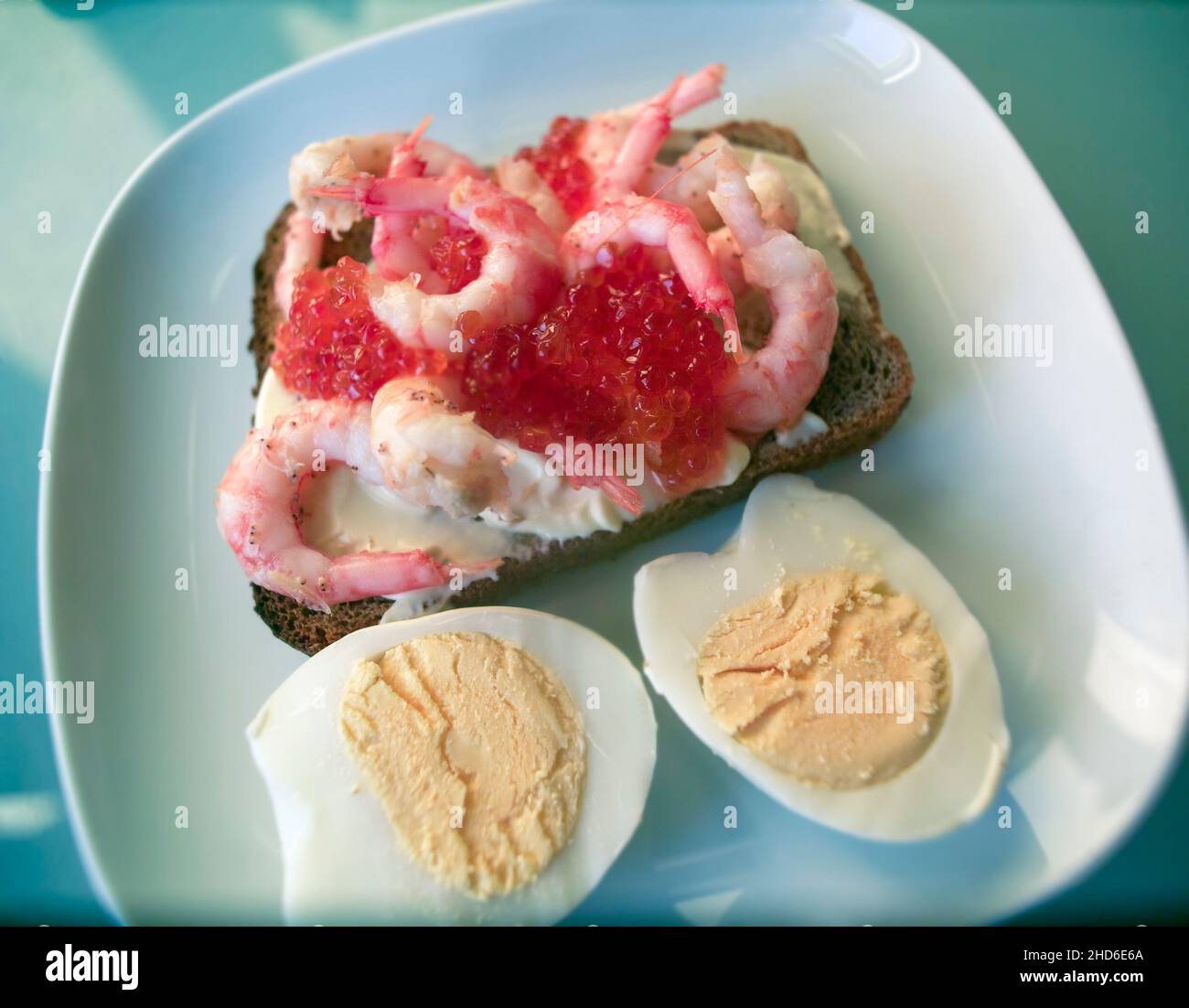 uova e panino con schrimps e caviale rosso su un piatto Foto Stock