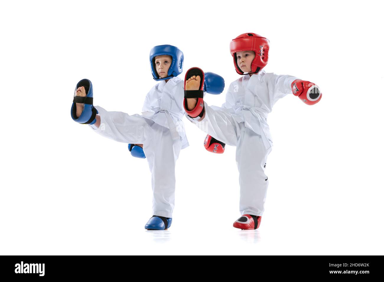 Studio girato di due bambini piccoli, ragazzi, atleti taekwondo che indossano dooks e uniformi sportive isolato su sfondo bianco. Foto Stock