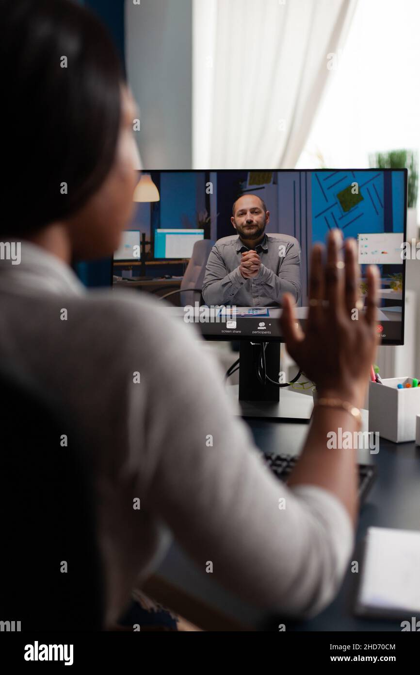 Donna che sventolano la mano alla videochiamata webcam con il manager, utilizzando la videoconferenza online per parlare di progetto di business. Dipendente che utilizza il computer per una riunione remota con l'uomo, lavorando da casa Foto Stock