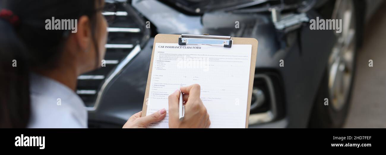 L'agente di assicurazione donna compila il modulo di assicurazione per danni auto dopo incidente stradale Foto Stock