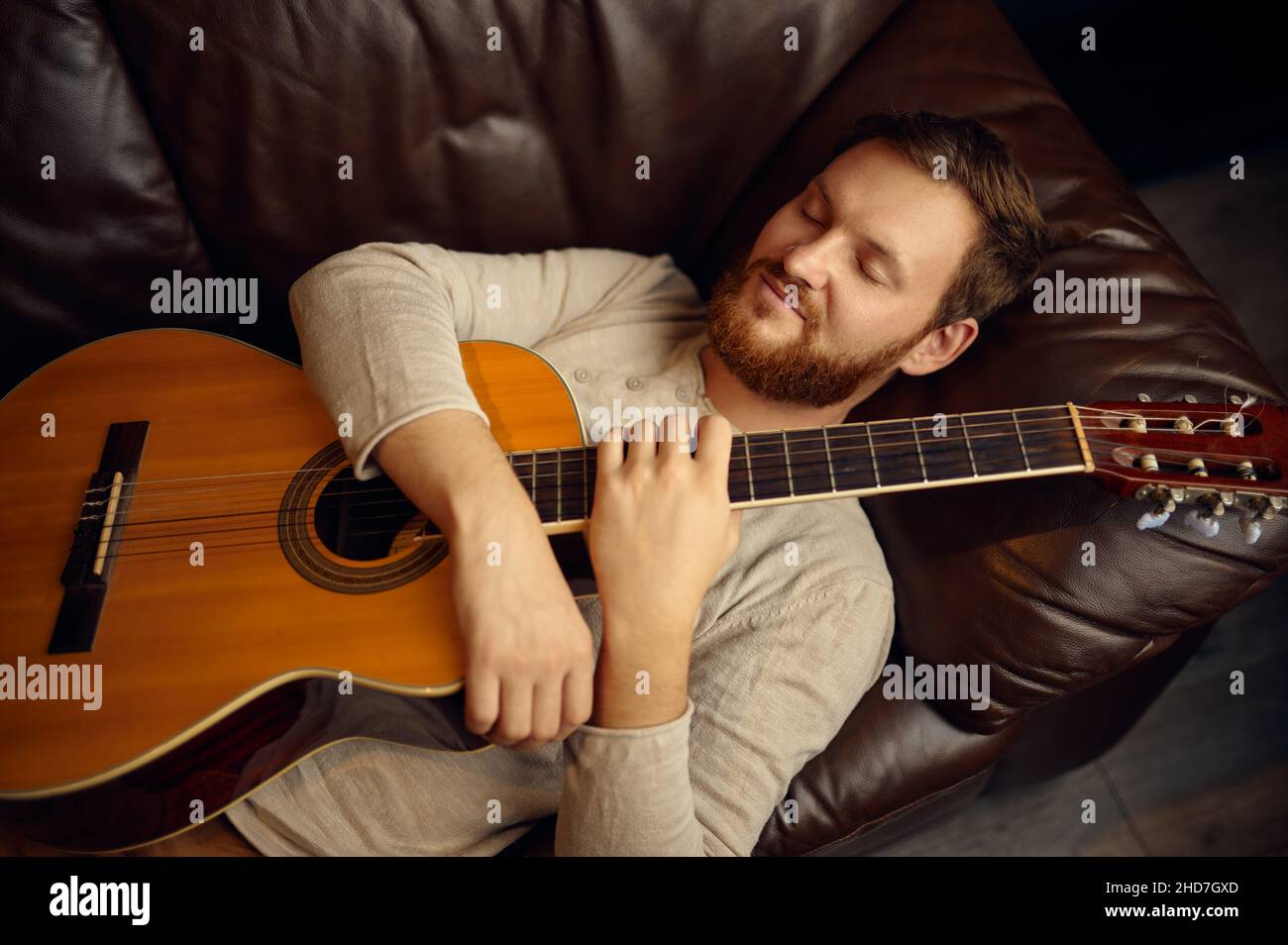 Giovane uomo sdraiato sul divano con la chitarra Foto Stock