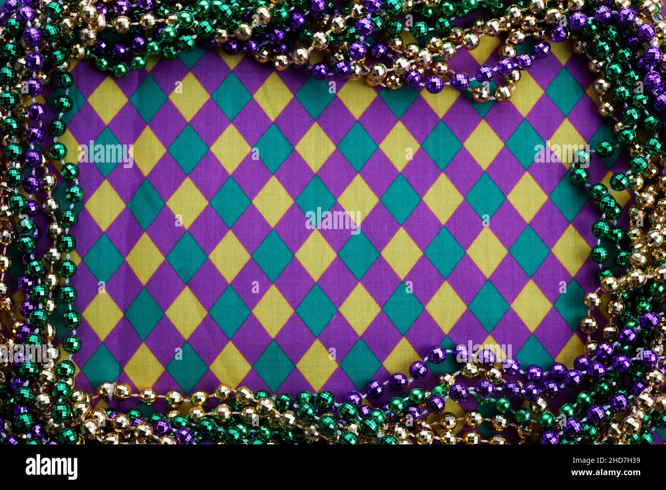 Cornice Mardi gras di tre colori di perline su diamanti fondo tessuto. Foto Stock