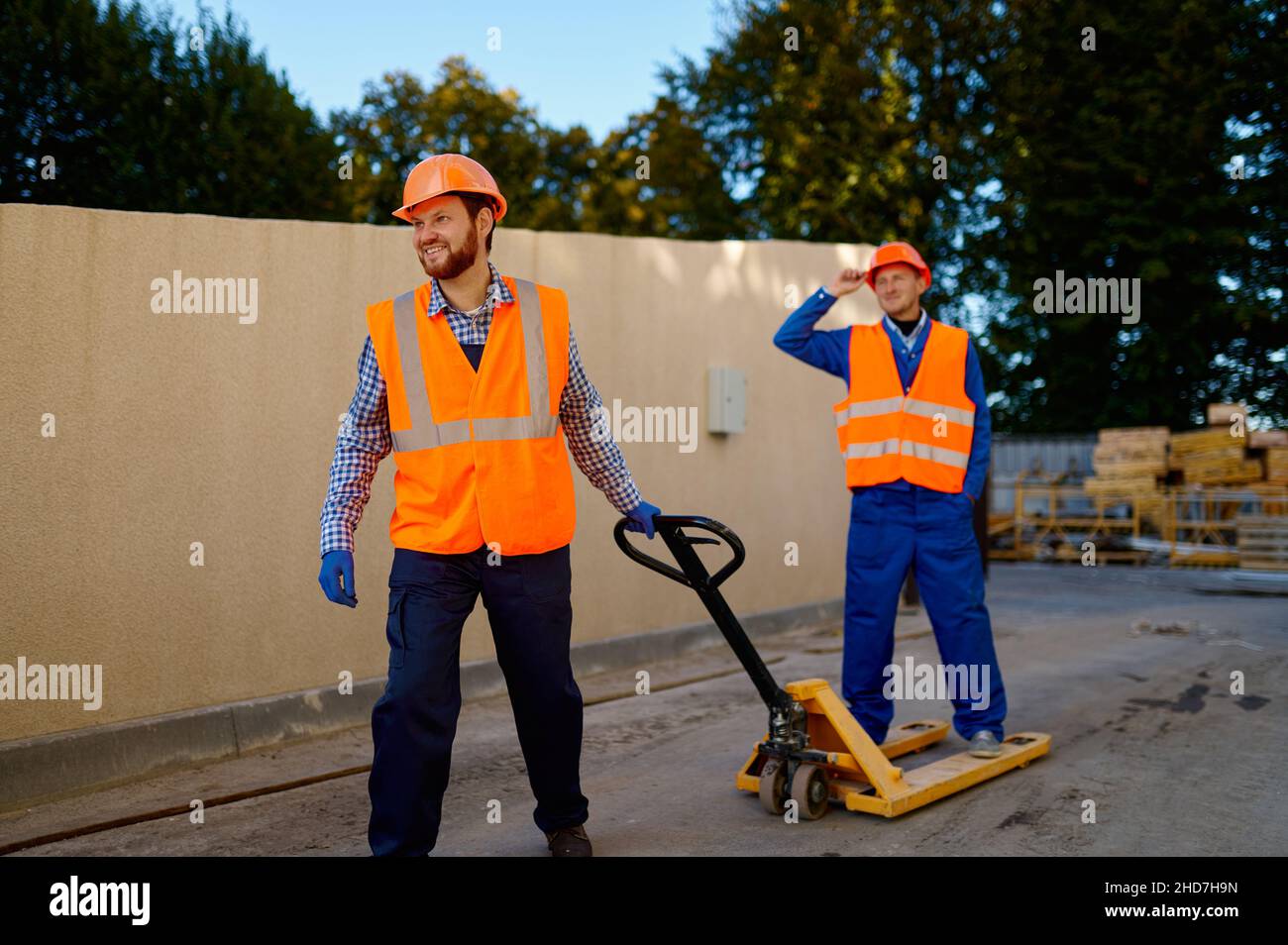 Operatore del costruttore che utilizza un transpallet con caricatore manuale Foto Stock