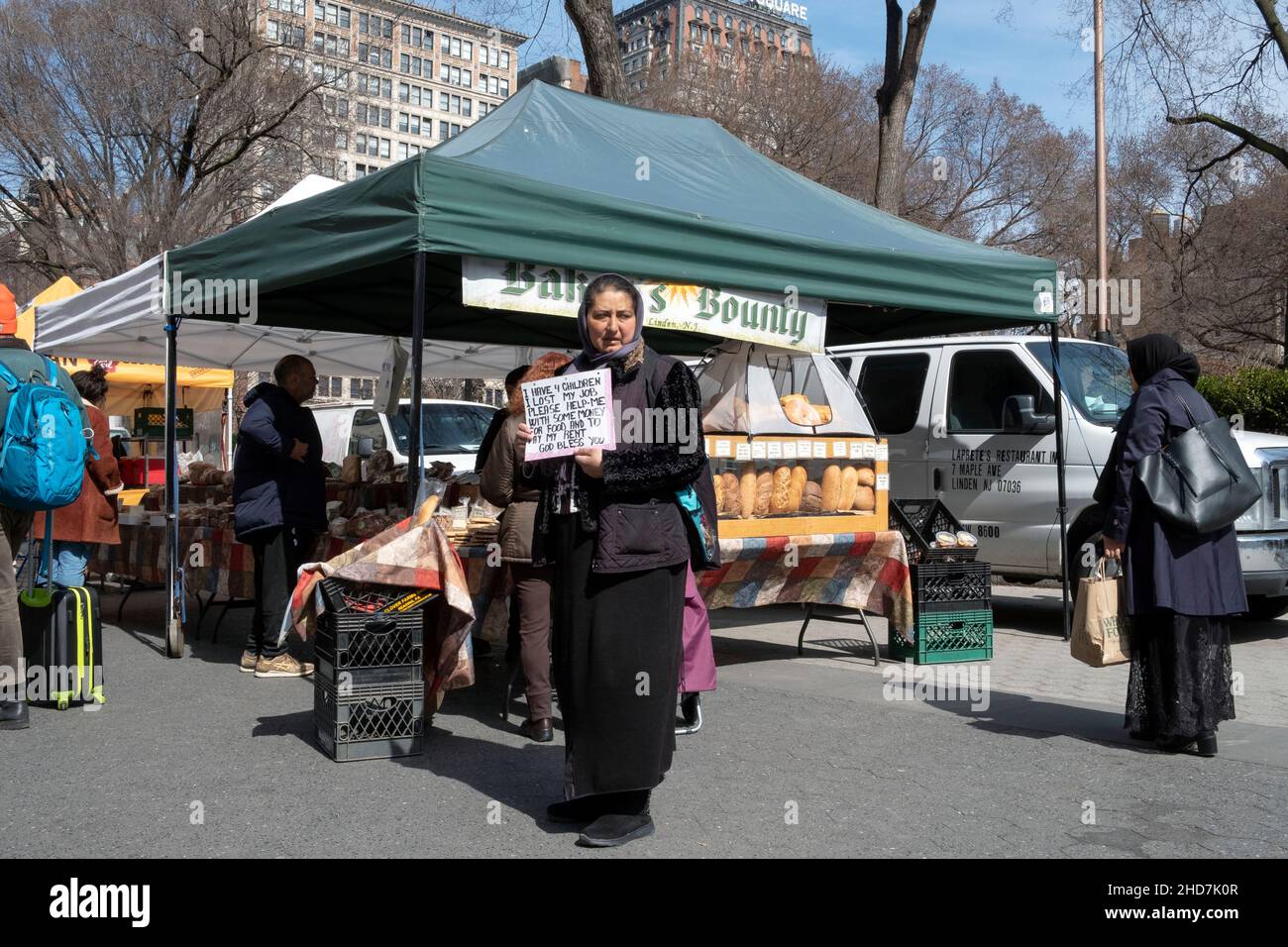 Una donna, probabilmente musulmana, che sollecita donazioni per se stessa e per i suoi figli all'Union Square Green Market di Manhattan, New York City. Foto Stock