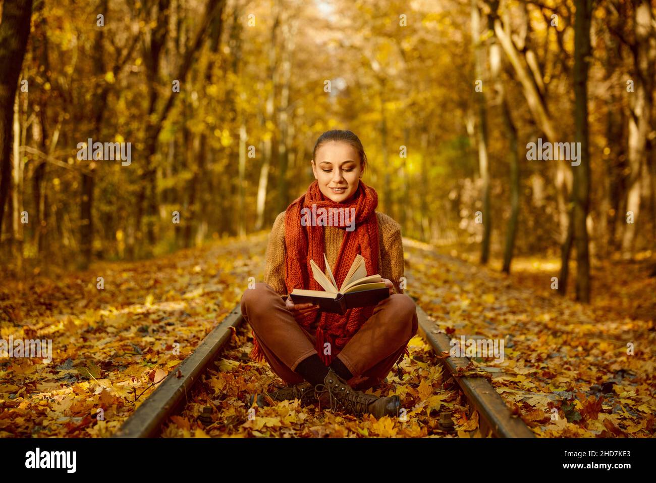 Donna che legge il libro mentre si siede binario ferroviario Foto Stock