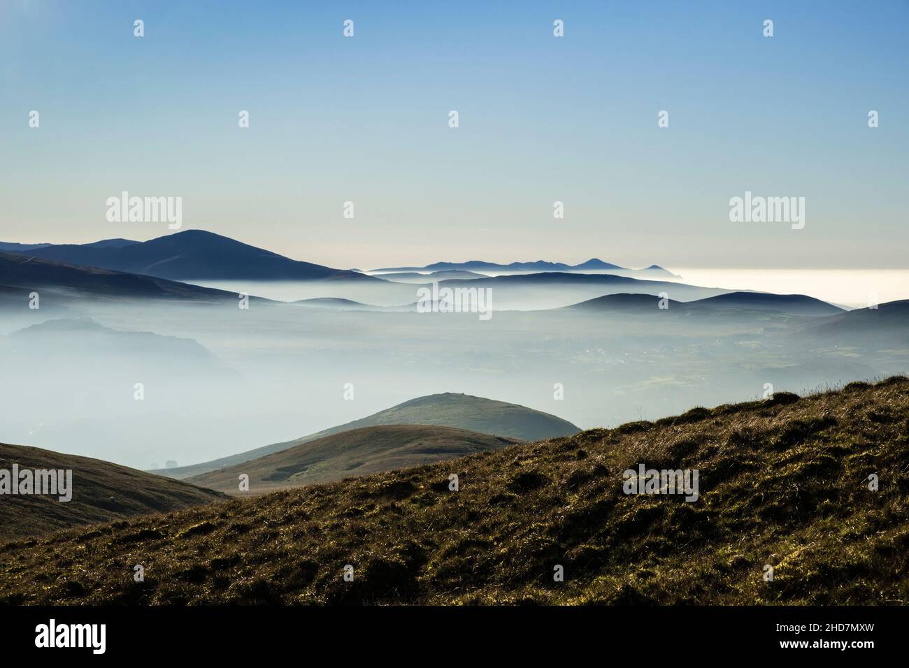 Vista da Moel Wnion con montagne retroilluminate in silhouette sopra le inversioni nuvole nel Parco Nazionale di Snowdonia. Abergwyngregyn, Gwynedd, Galles, Regno Unito Foto Stock