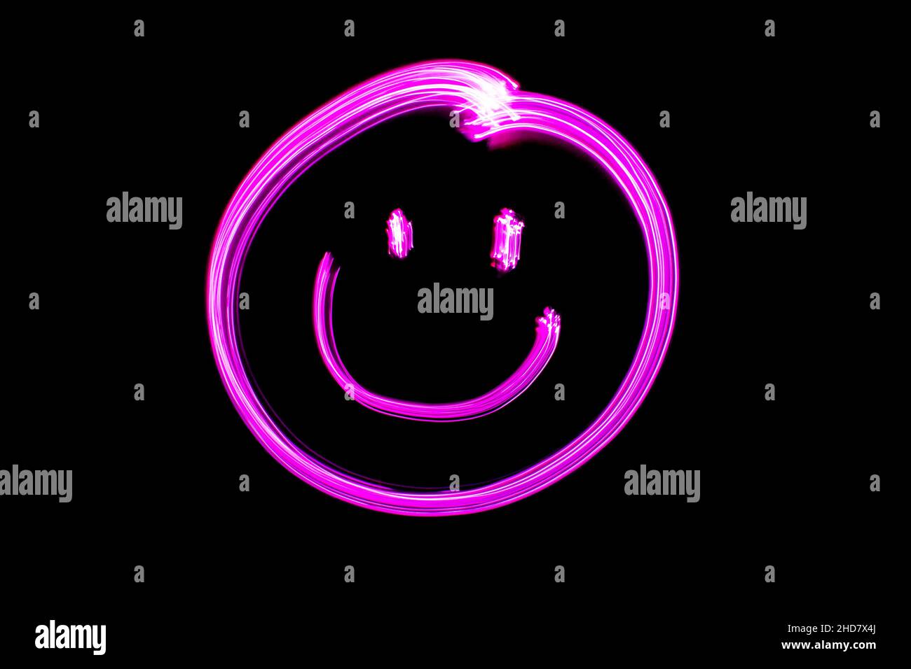 Viso sorridente al neon, viso sorridente rosa dipinto chiaro su sfondo nero. Espressioni facciali emoji. Foto Stock
