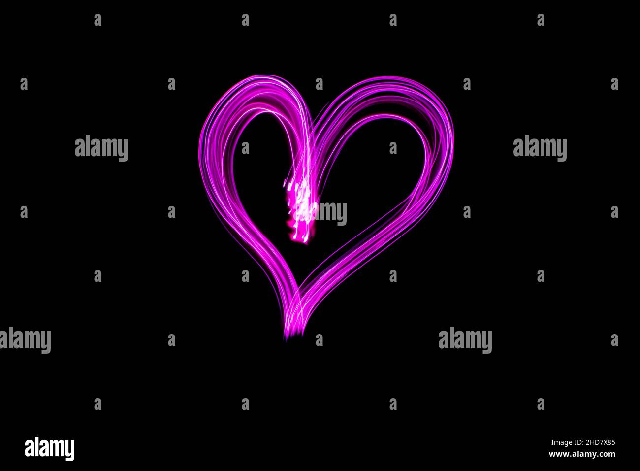Pittura leggera della forma del cuore. Cuore disegnato con luci rosa su sfondo nero. Fotografia a lunga esposizione. Febbraio 14 San Valentino sfondo. Foto Stock