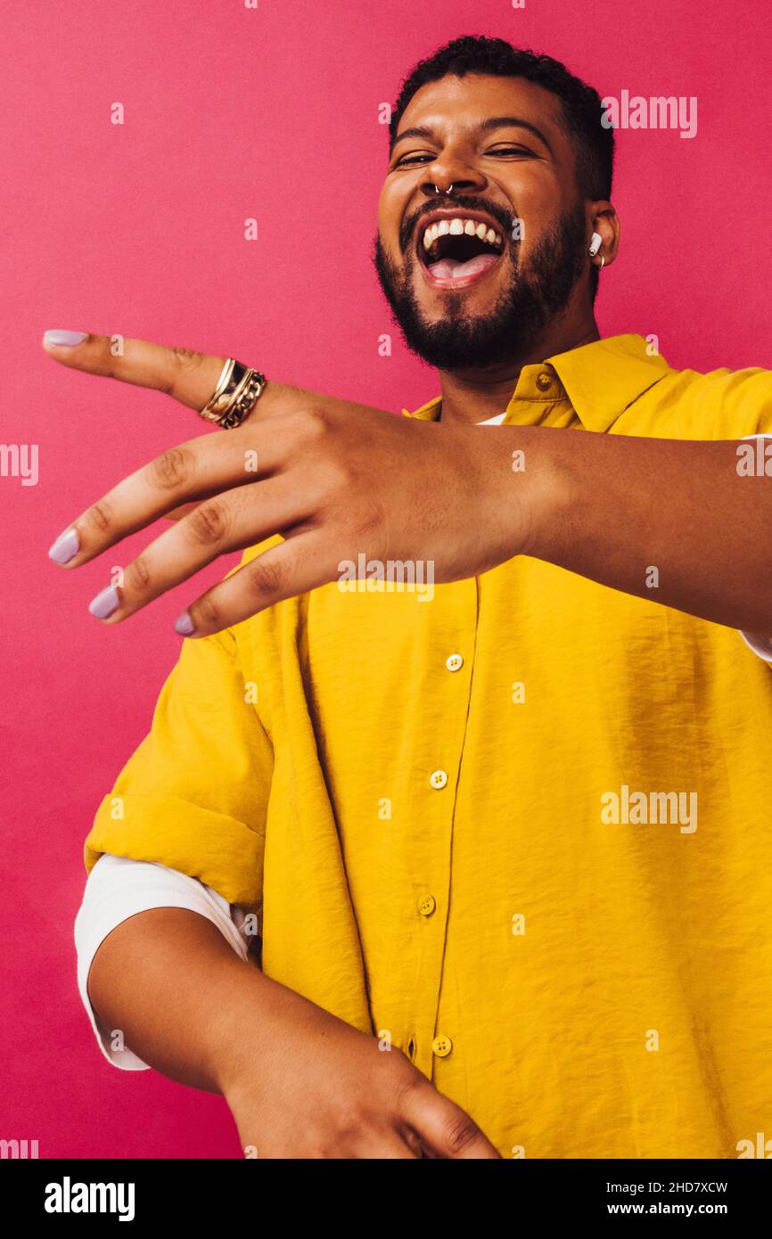 Balli e streaming in studio. Un giovane felice che balla mentre ascolta la sua musica preferita con gli auricolari wireless. Sorridente giovane uomo in piedi Foto Stock