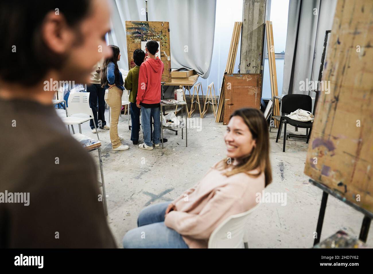 Amici felici che si divertono all'interno della sala d'arte all'università - Focus on students painting on background Foto Stock
