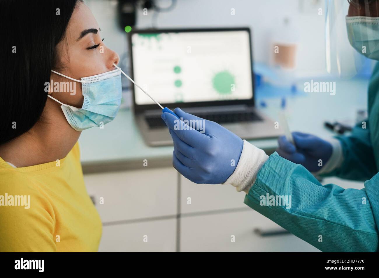 Medico che fa il test nasale alla giovane donna in clinica medica per l'infezione da coronavirus - fuoco sulla mano che tiene il tampone Foto Stock