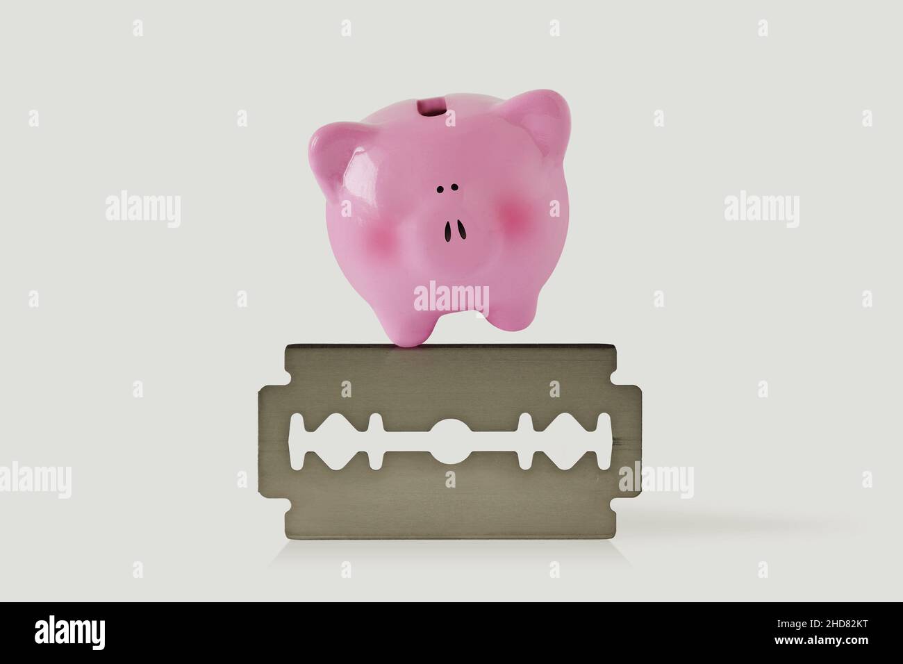 Piggy banca su lama di rasoio - concetto di economia e di rischio finanziario Foto Stock