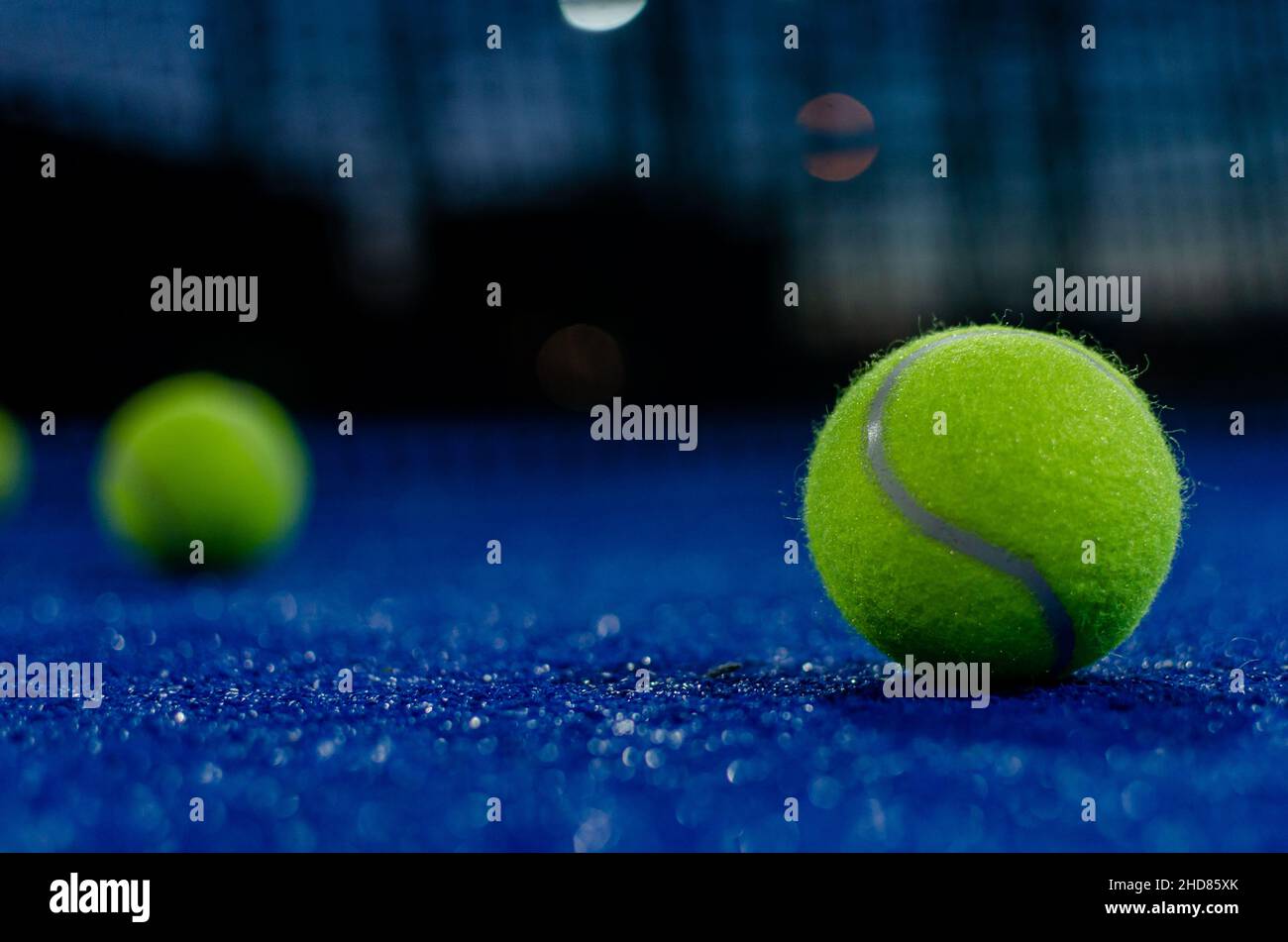 Messa a fuoco selettiva. Due palle da paddle tennis su un campo da paddle blu di notte. Concetto sportivo racket. Foto Stock