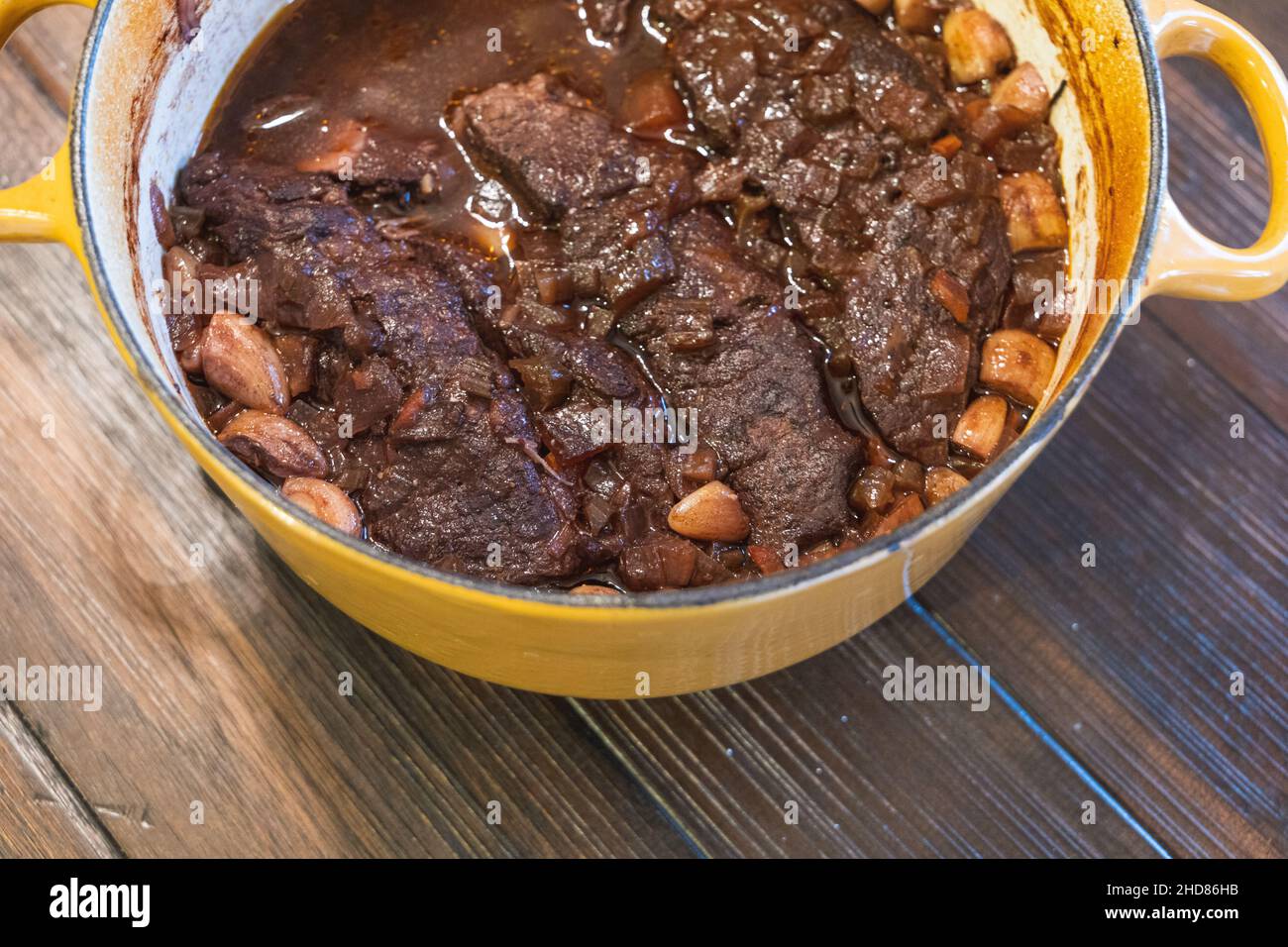 Un forno olandese giallo con costolette di manzo brasate in casa al vino e all'aglio Foto Stock