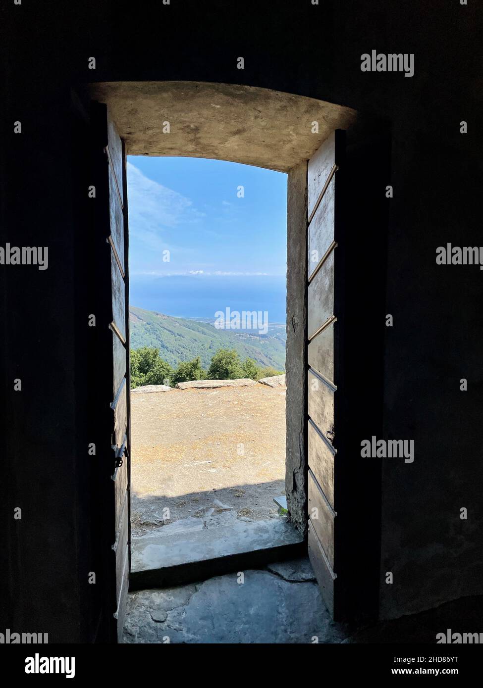 Vista sul Mar Mediterraneo attraverso la porta della cappella di San Bertuli in Monacia-d'Orezza, Castagniccia, Corsica. Verticale. Foto Stock