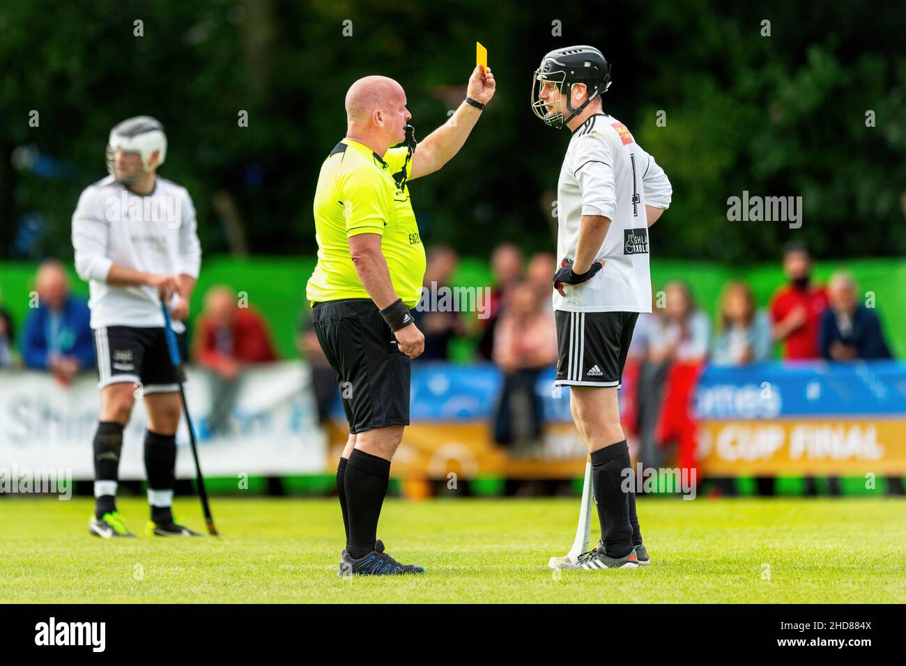 L'arbitro prenota un giocatore. Lovat / Kinlochshiel nella finale della Coppa Camanachd di Tulloch Homes, disputata a Mossfield, Oban. Foto Stock