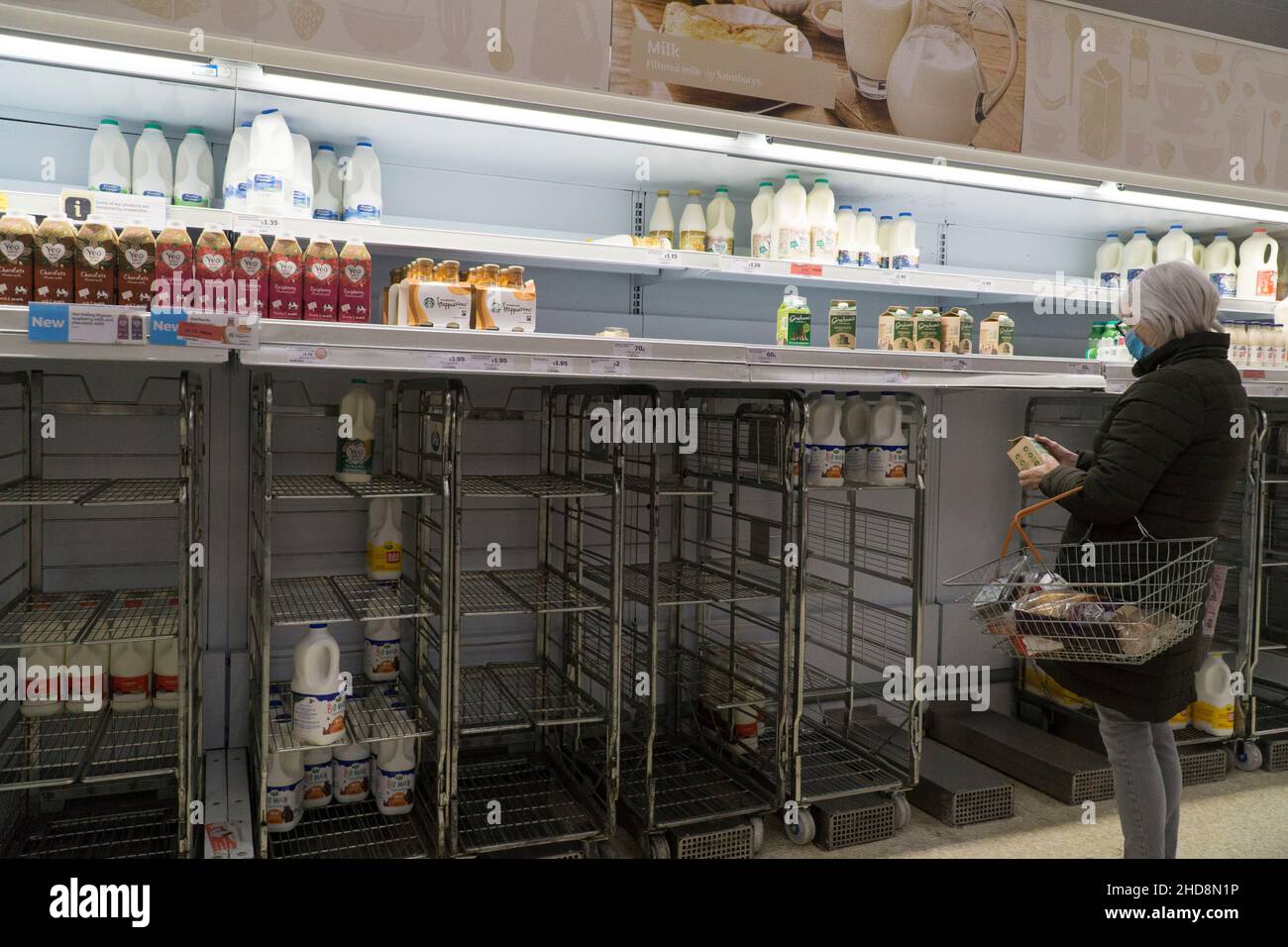 Londra, Regno Unito, 4 gennaio 2022: Il giorno dopo la festa bancaria di Capodanno una donna contempla le sue limitate opzioni di acquisto del latte in questa filiale di Sainsbury's a Clapham. Avevano solo una piccola quantità di latte a pranzo, e nessuno dei tipi più economici di marca propria. Anna Watson/Alamy Live News Foto Stock