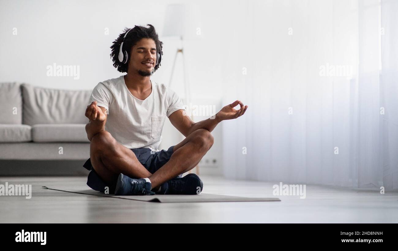 Pratica di meditazione. Rilassato uomo nero meditando a casa in posizione Lotus Foto Stock