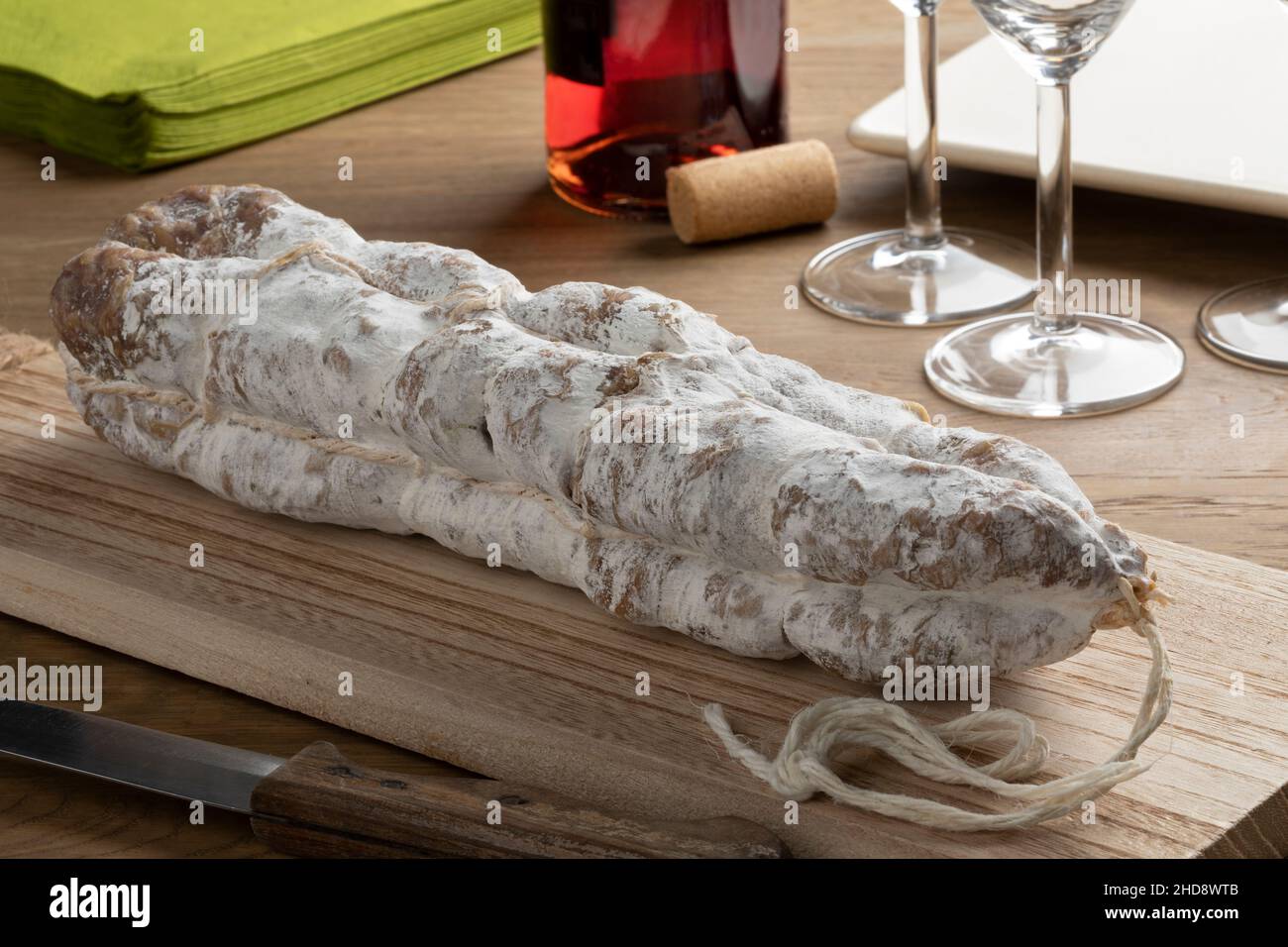 Salsiccia secca francese intera fatta a mano, saucisson sec, su un tagliere di legno Foto Stock