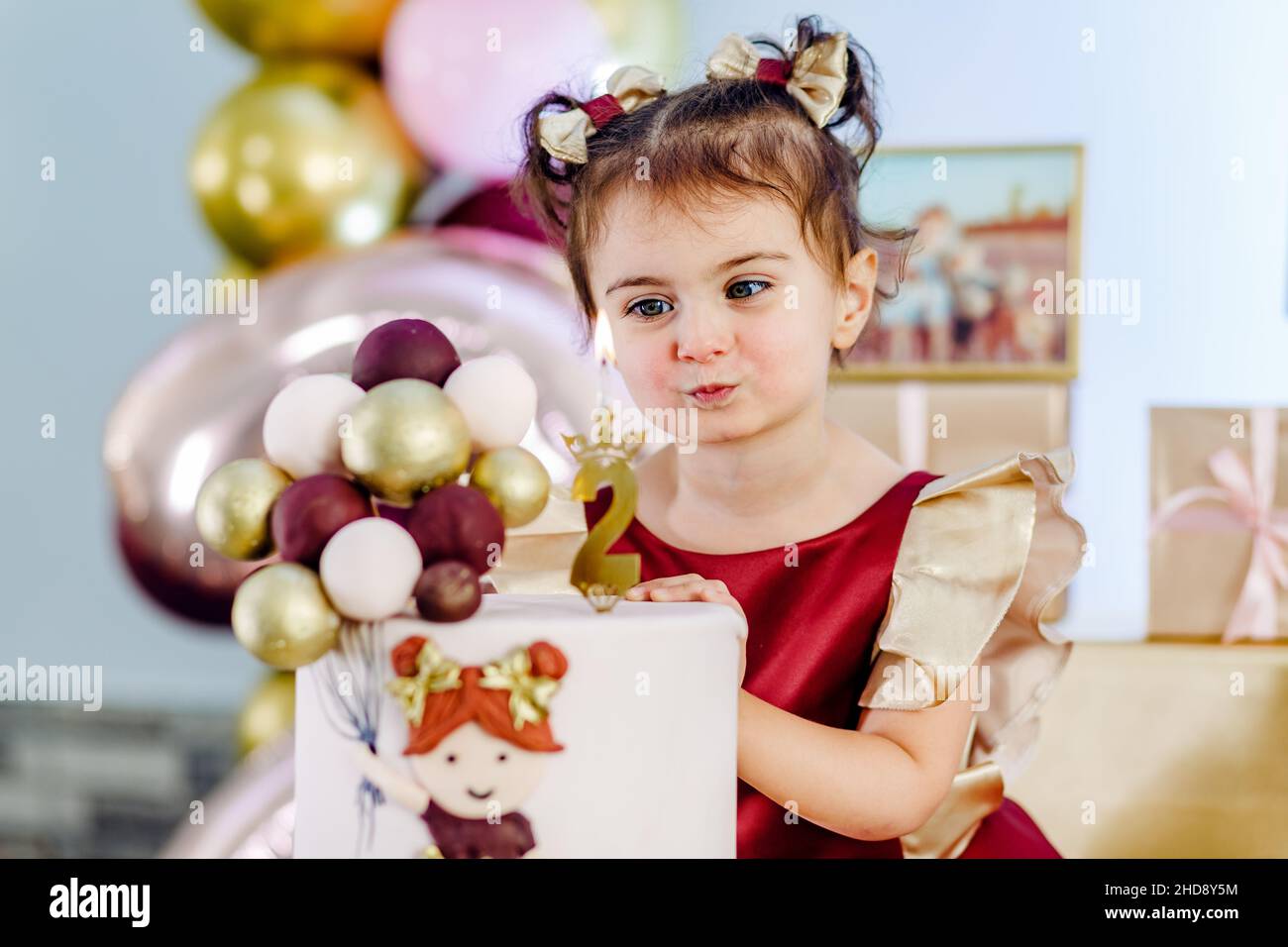 Ritratto di bella ragazza sorridente bambino in piedi accanto alla torta di compleanno e soffiando fuori candela. Bella foto compleanno ragazza bambino Foto Stock