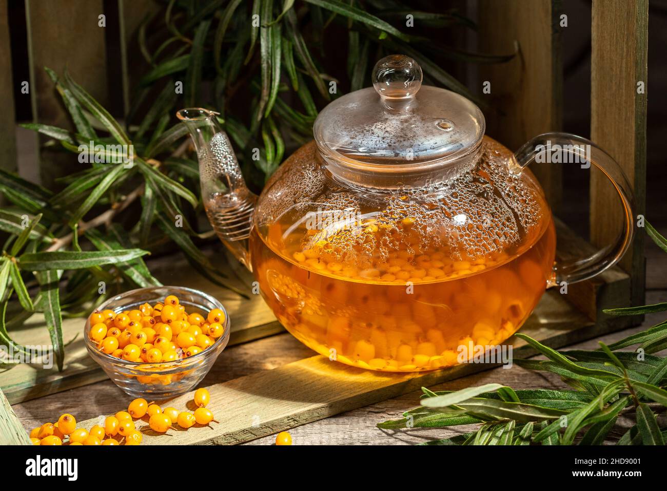 Bevanda invernale calda a base di frutti di bosco di fieno di mare in un bollitore di vetro su un tavolo di legno Foto Stock