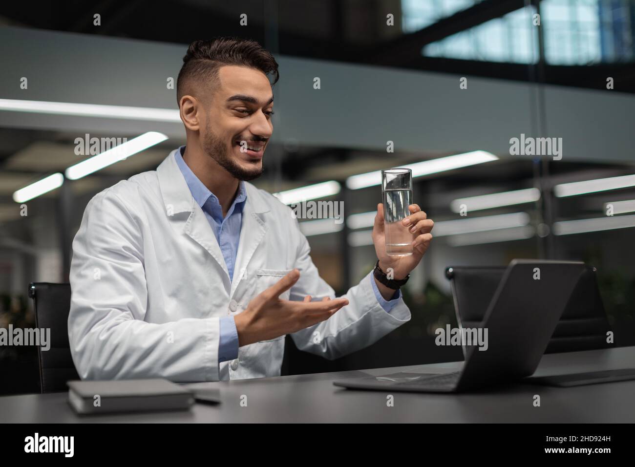 Bel giovane scienziato musulmano che usa il laptop in ufficio Foto Stock