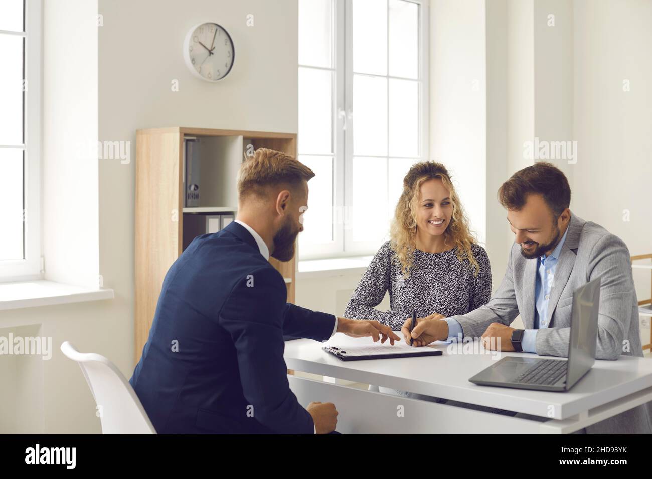 La famiglia felice firma il contratto d'affitto o d'acquisto dato loro dal responsabile della banca o dall'agente immobiliare. Foto Stock