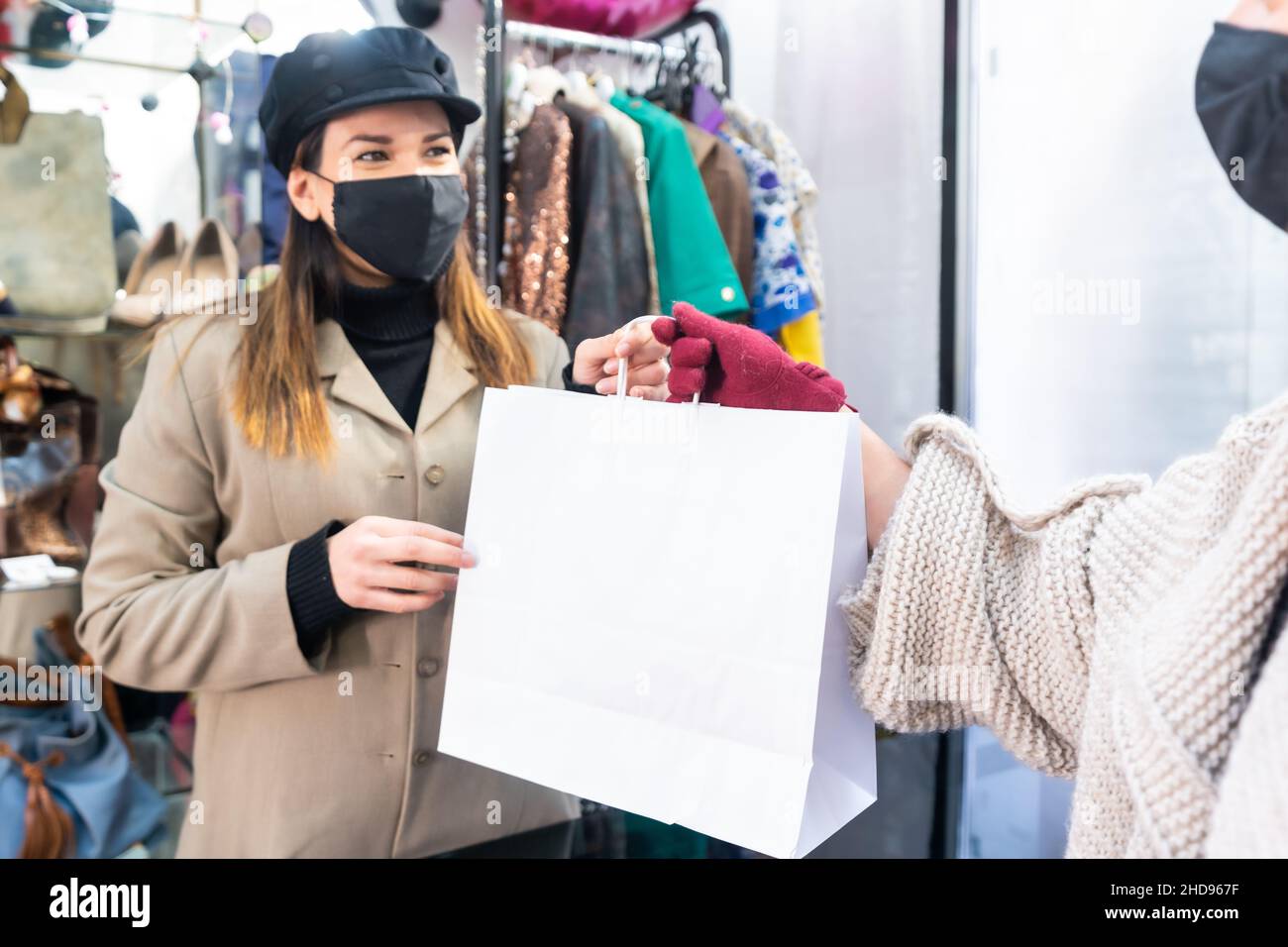 Dipendente con maschere in un negozio di abbigliamento consegna abiti a un cliente, misure di sicurezza nel coronavirus pandemic, covid-19 Foto Stock