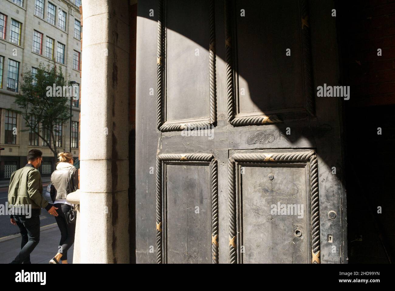 Un giovane uomo e una donna che camminano lungo una strada di Londra con l'uomo che tocca il fondo della donna Foto Stock