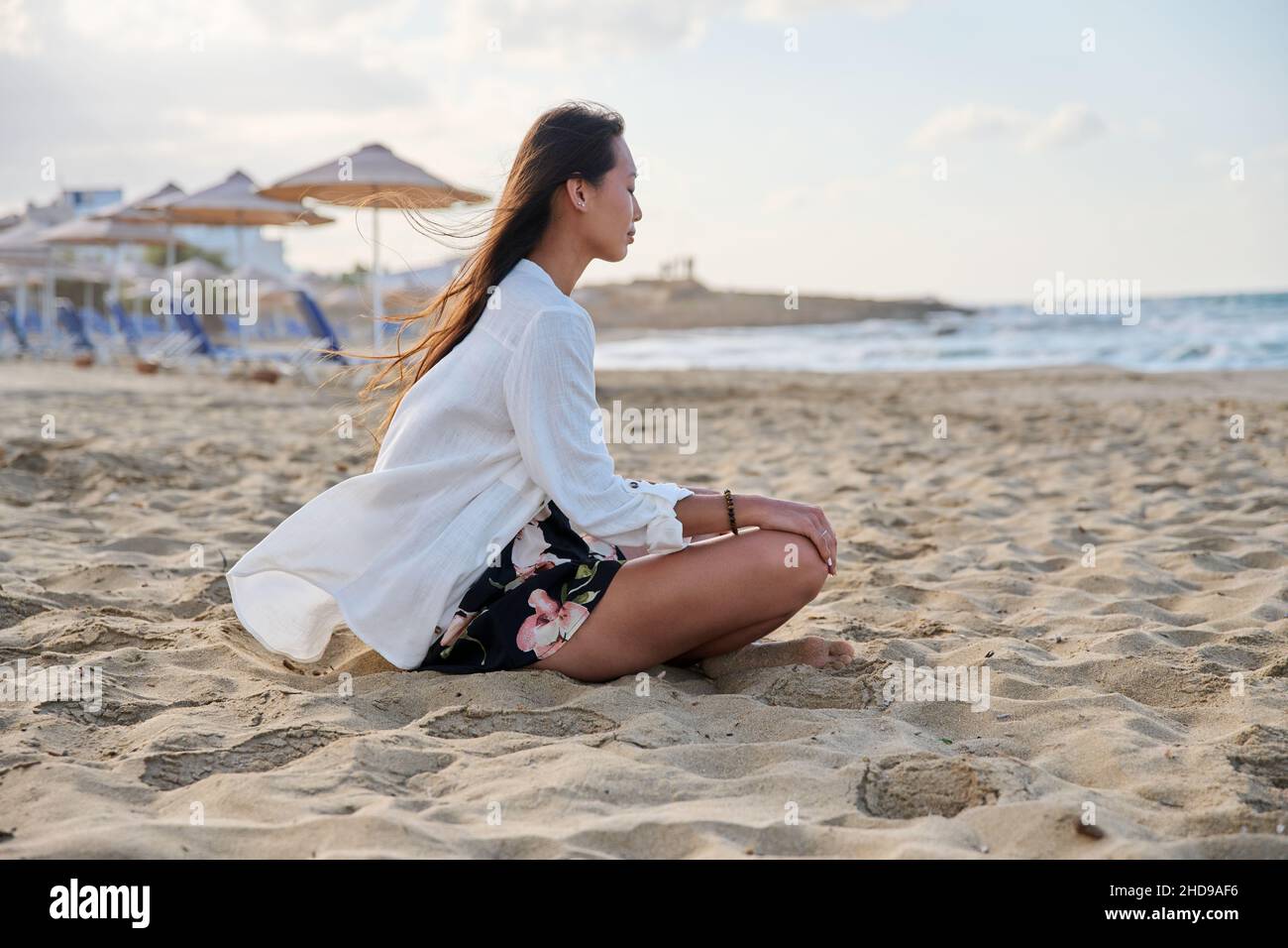 Giovane donna rilassata seduta in posizione lotus sulla spiaggia, mattina mare natura Foto Stock