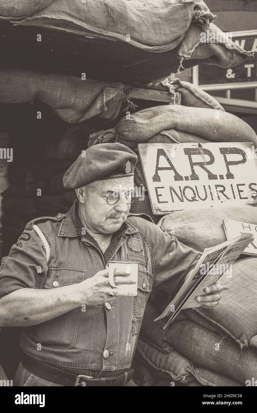 Mono close up of wartime, 1940 ARP warden (Air raid Precauzioni) lettura giornale d'epoca, Severn Valley Heritage Railway 1940s WW2 evento estivo UK. Foto Stock