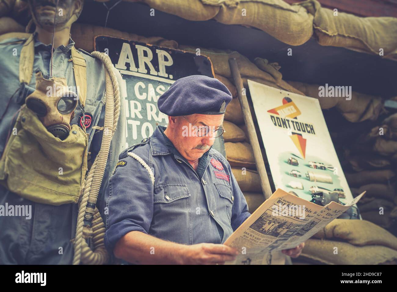 Primo piano di tempo di guerra, 1940 ARP warden (Air raid Precauzioni) lettura giornale d'epoca, Severn Valley Heritage Railway 1940s WW2 evento estivo Regno Unito. Foto Stock