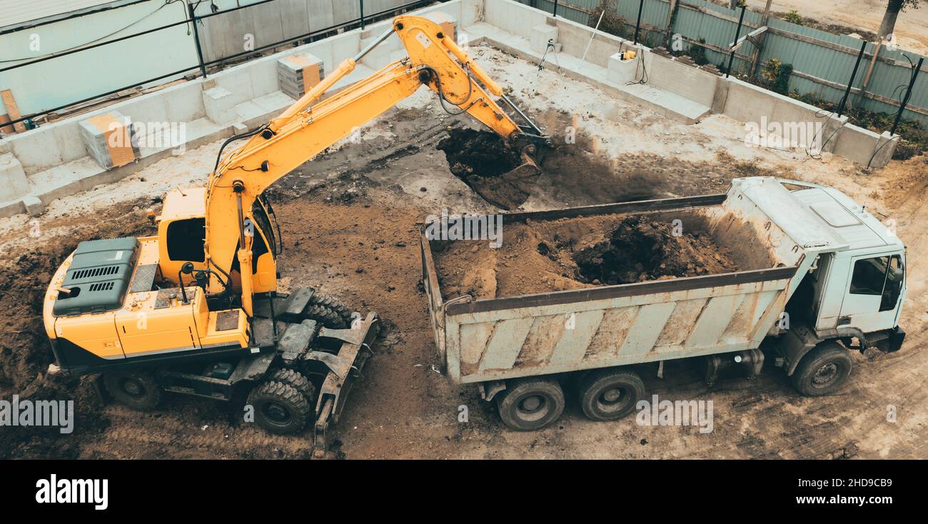 Scavatore scava pozzo fondazione. Lavori di scavo in cantiere, vista dall'alto aerea. Foto Stock