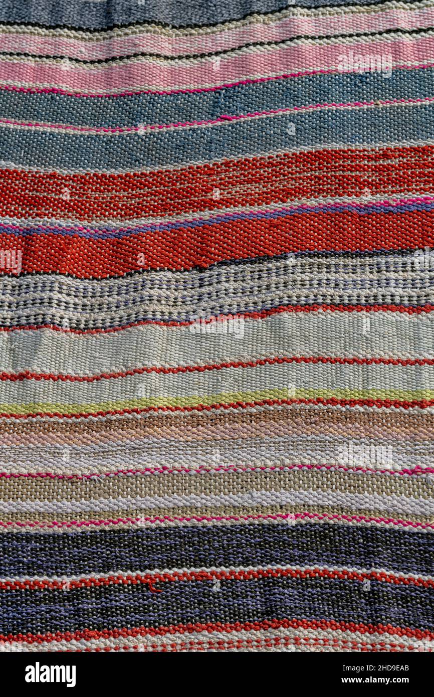 tessuto tessuto a righe con design multicolore per l'uso come tappeto o tappeto, tessitura fatta a mano su un rivestimento del pavimento in tessuto color arcobaleno. Foto Stock