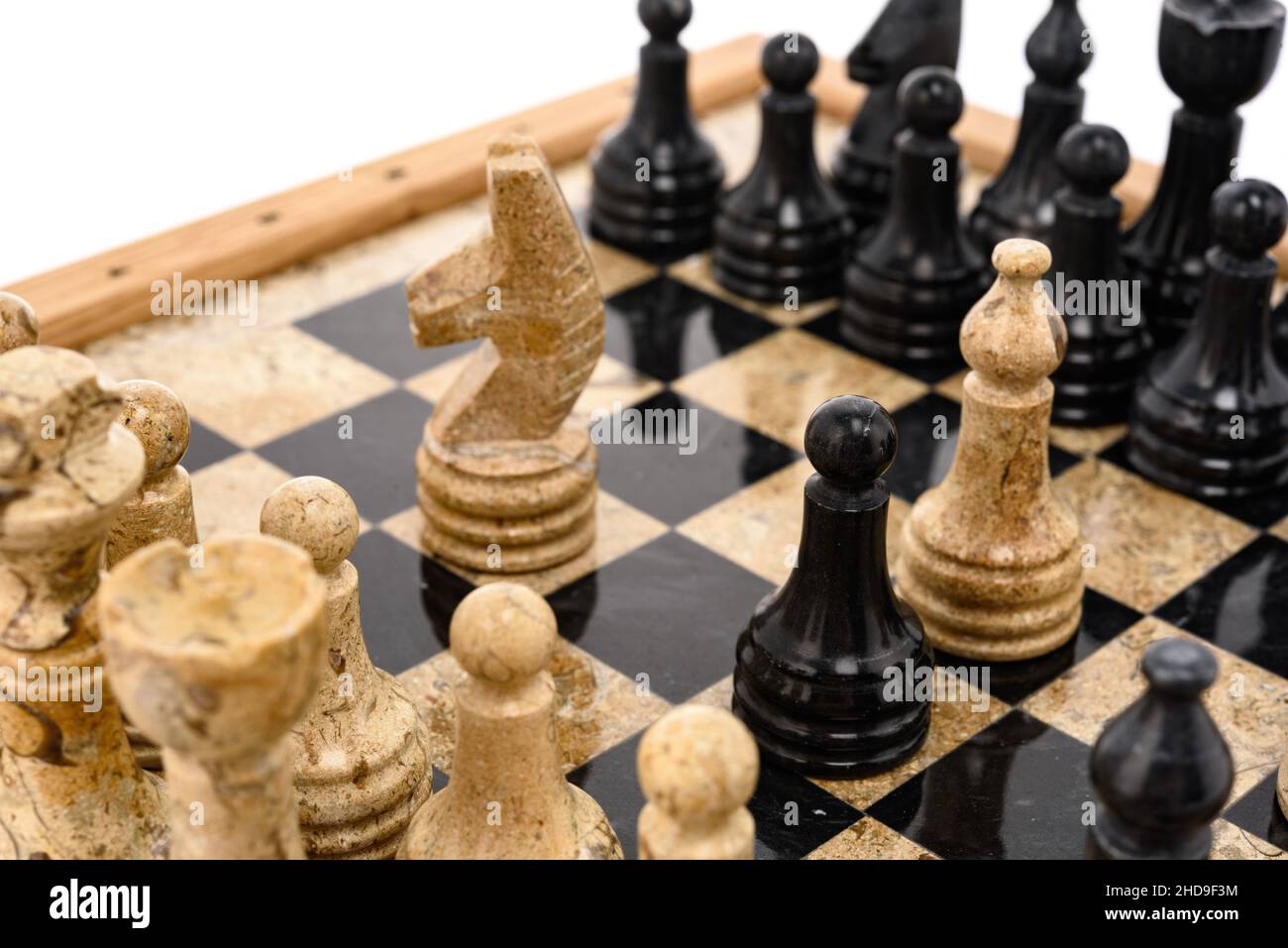 pezzi di scacchi come rivali, al centro su scacchiera in marmo corallo nero e beige. Primo piano del concorso di concetto di gioco, Torneo classico. Foto Stock