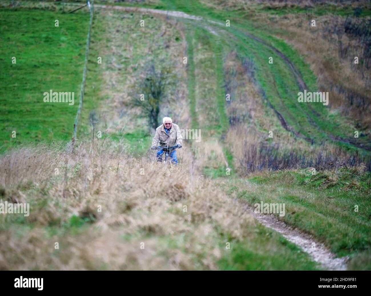 Un ciclista casual peddle bike che corre lungo una pista non fatta che attraversa la campagna aperta, salisbury Plain, Wiltshire UK Foto Stock