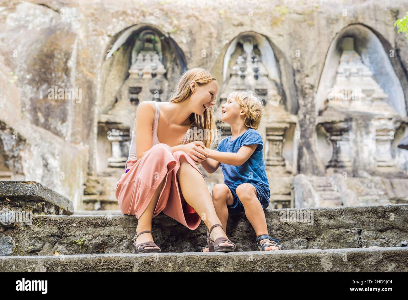 Mamma e figlio su sfondo di Gunung Kawi. Antico scolpito nel tempio in pietra con tombe reali. Bali, Indonesia. Concetto di viaggio con bambini Foto Stock