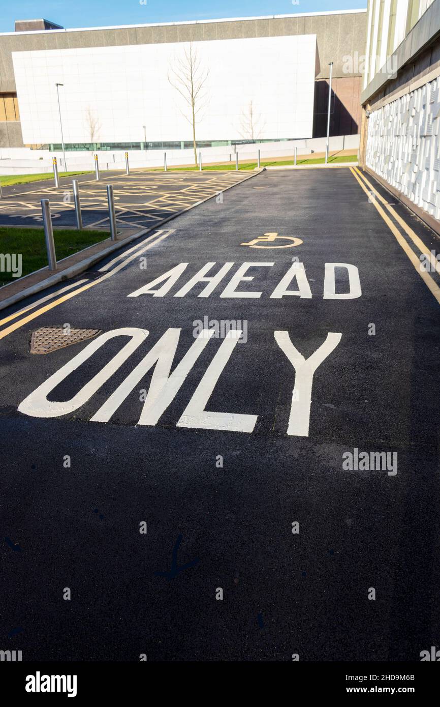 Avanti solo lettere dipinte su tarmac e simbolo disabili accanto a pannelli decorativi in rilievo sulla biblioteca centrale Hanley a Stoke on Trent Foto Stock