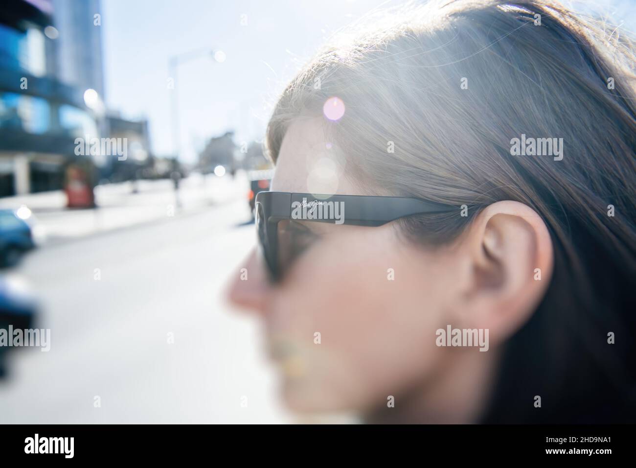 Vista laterale della giovane bella donna che indossa occhiali da sole di lusso American Maui Jim Foto Stock