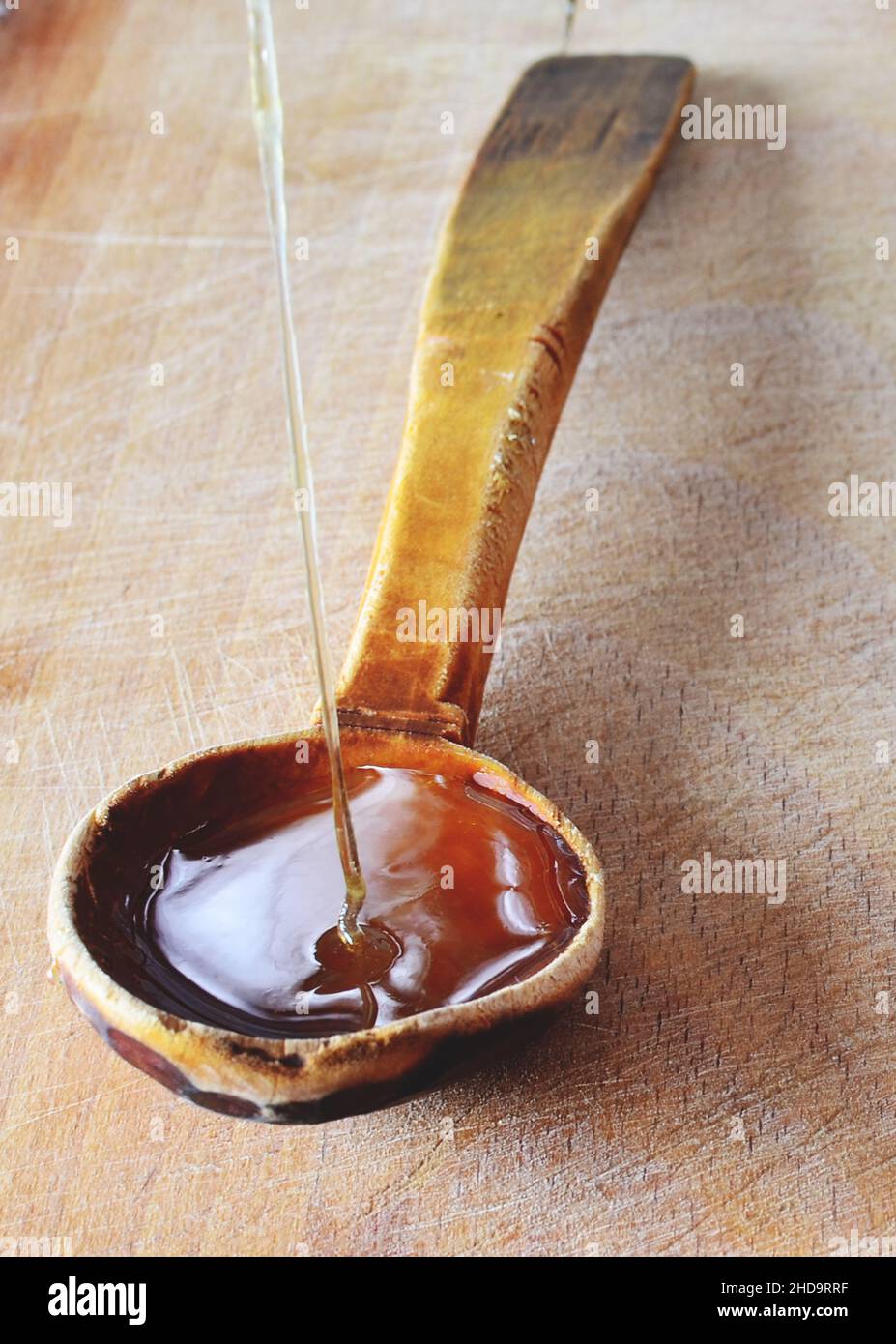 Miele biologico fresco naturale versato in un cucchiaio di legno. Foto Stock