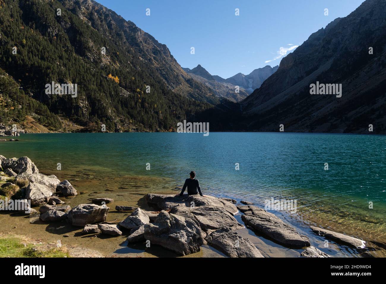 Giovane viaggiatore seduto su rocce sulla riva del Lac de Gaube Foto Stock