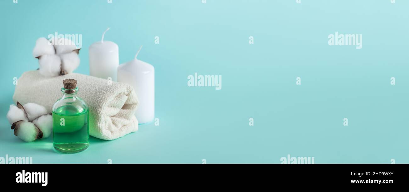 Prodotti naturali biologici di bellezza per spa e aromaterapia. Olio essenziale aromatico, candele e un asciugamano su sfondo blu. Concetto di relax, luogo Foto Stock