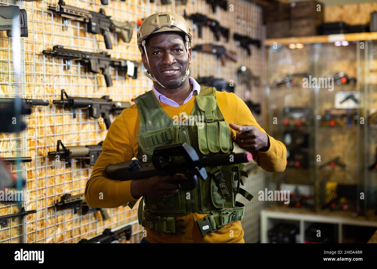 Ragazzo afro-americano in attrezzature militari con arma in negozio militare Foto Stock