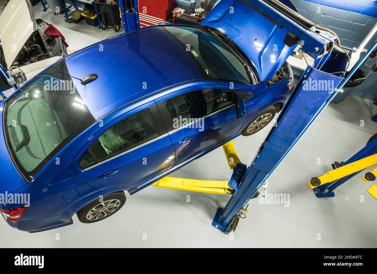 Moderna vettura compatta con manutenzione in garanzia. Veicolo su un sollevatore automobilistico all'interno del centro di assistenza della concessionaria. Tema trasporti. Foto Stock