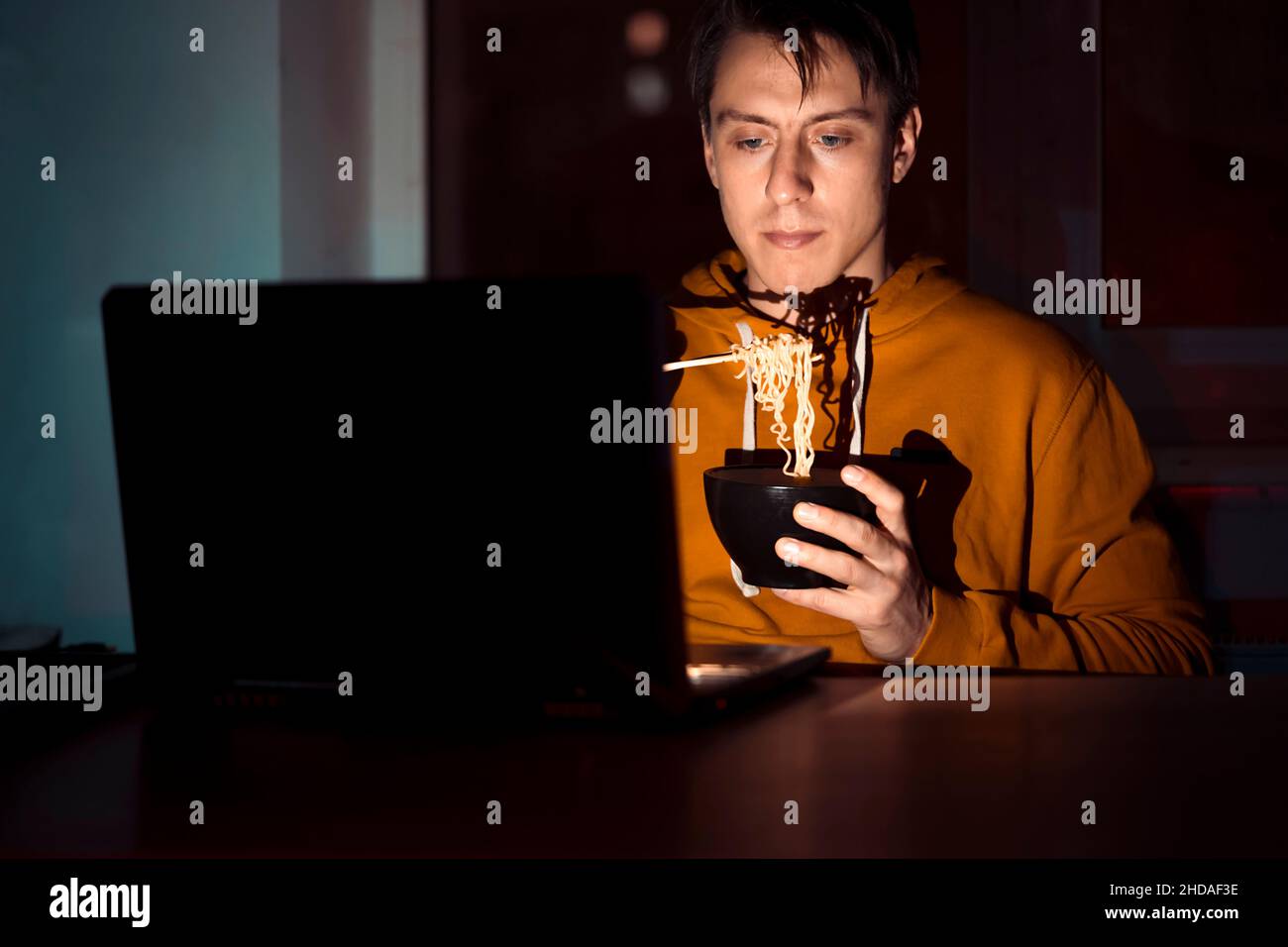 L'uomo sta mangiando noodles e guardando i film. Foto Stock