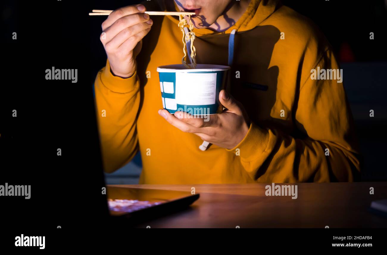 L'uomo sta mangiando noodles e guardando i film. Foto Stock