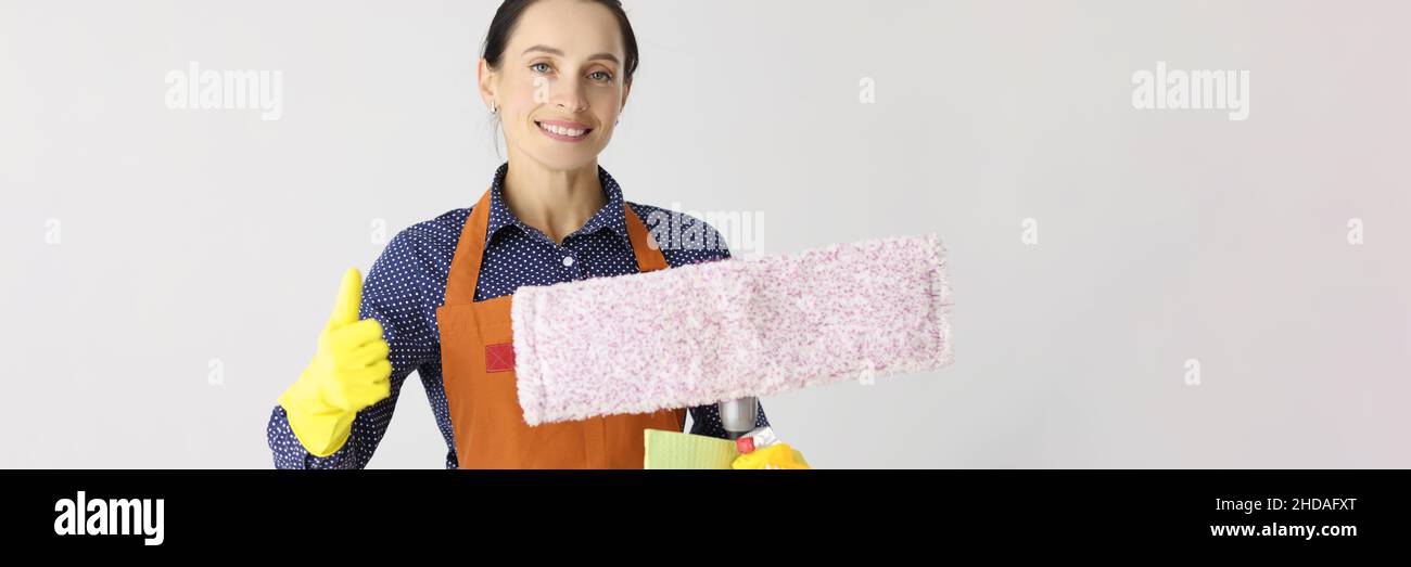 Donna sorridente che pulisce la donna tiene i pollici in su Foto Stock