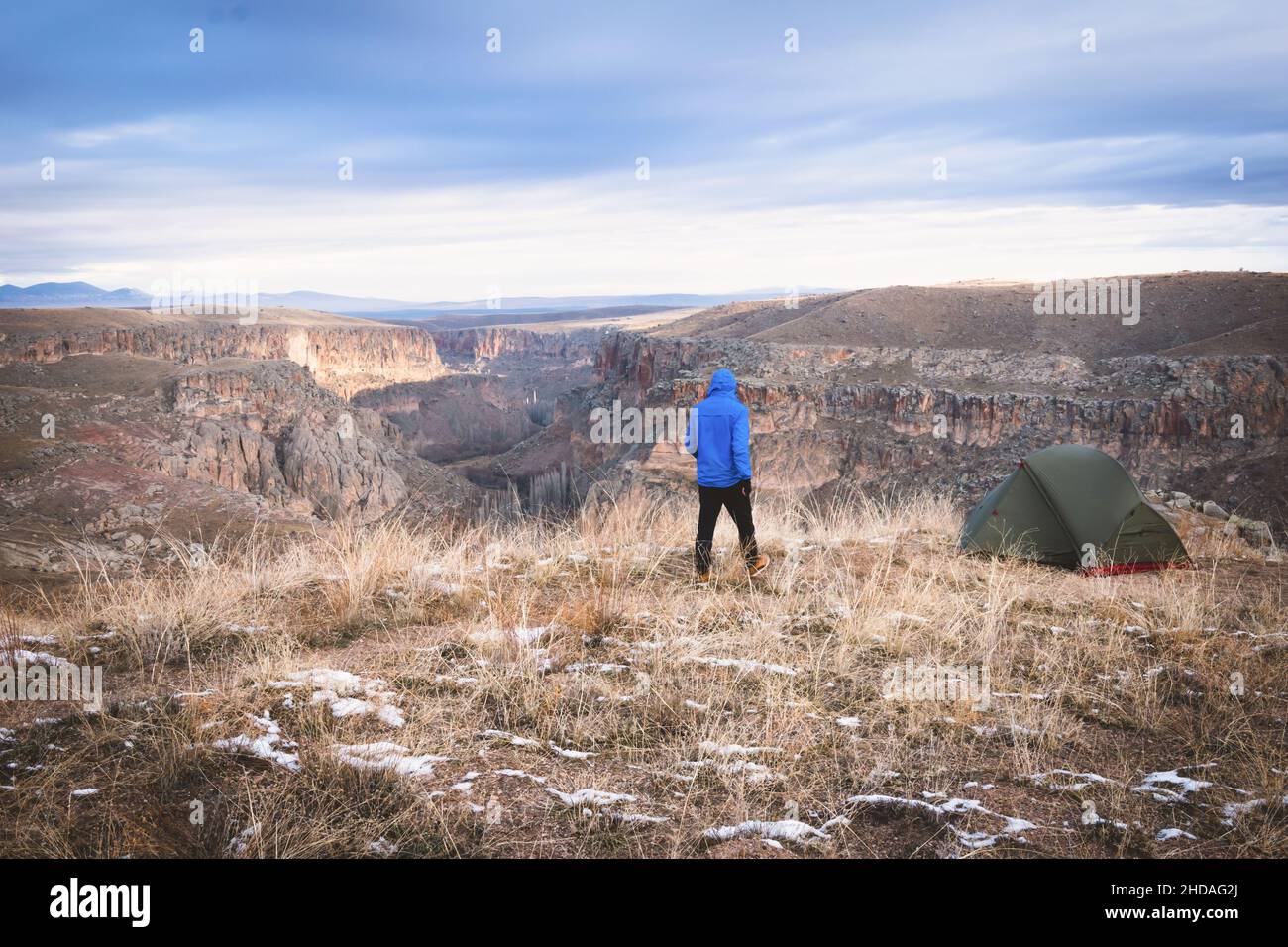 La persona sta camminando verso la tenda verde mentre osserva il paesaggio della valle di Ihlara. Camping in un posto panoramico in Turchia. Avventura e tempo nella natura. Foto Stock