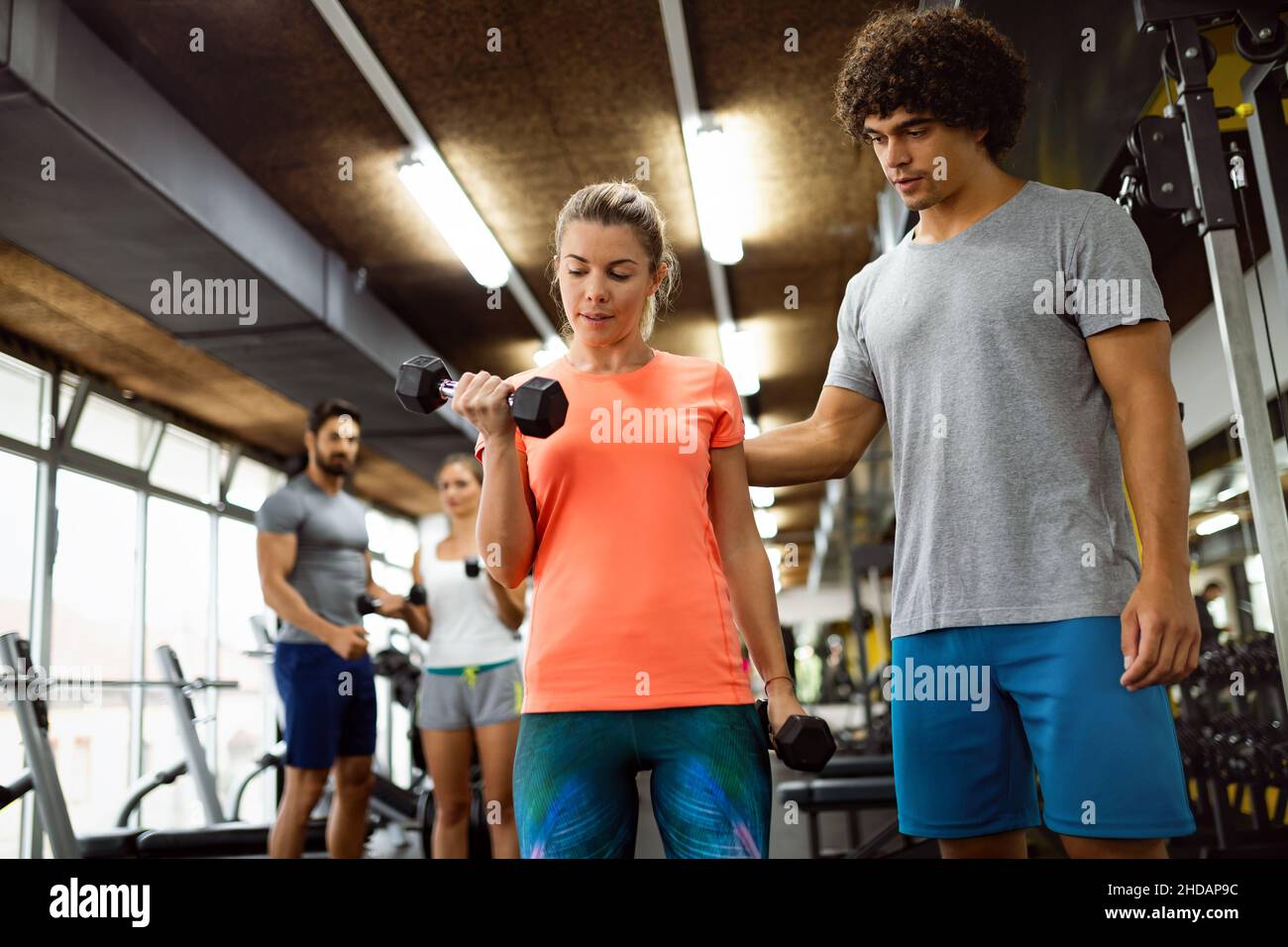 Fit donna felice con il suo personal fitness trainer in palestra esercitandosi con i manubri Foto Stock